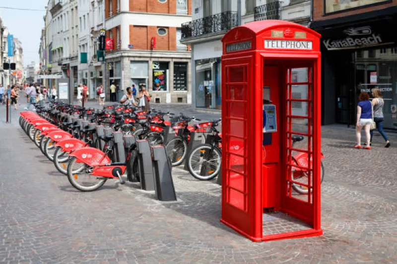 red phone booth and bike sharing station on a busy city street